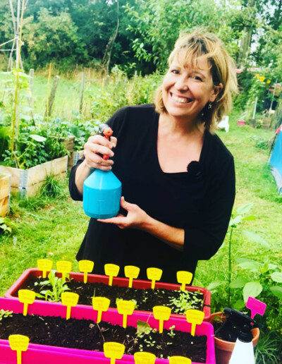 Christelle Delmote en train de pulvériser ses plants dans son potager en permaculture